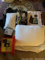 Photo showing two pillows, packaging for Sylvania portable DVD player, and a full-color table light boxed.