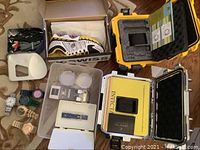 Overall view: sneaker in box, watches, cases, cables and accessories arranged on floor