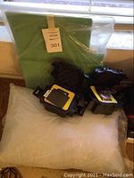 Two green plastic bins leaning against window, black hard cases on pillow