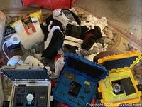 Three closed protective cases with pile of socks and t-shirts visible behind