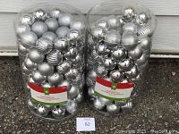 Two large clear plastic containers filled with assorted silver Christmas ball ornaments, front view.