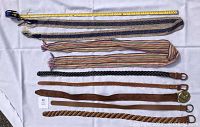 Full view of all seven women's belts laid out side by side with measuring tape for lengths
