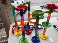 Assembled marble maze showing multiple levels of colorful track pieces including spiral funnels and vertical tubular columns with translucent segments.