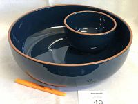 Side angle view showing the large dark blue chip bowl with smaller dip bowl inside and terracotta rim, with a pen for scale