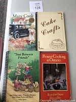Four books stacked: 'Liar, Liar Pants on Fire' by Mary Cook, 'Cake Crafts', 'Just Between Friends' by Glad Tidings Ladies Women's Ministries, 'Pioneer Cooking in Ontario'