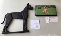 Photo showing the black metal Great Dane dog silhouette sign next to the Great Dane wallet with tags and warranty card.