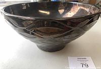 Side view of the large handcrafted decorative bowl showing embossed geometric leaf-like patterns and dark glossy surface.