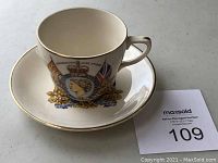 Oblique view of the commemorative tea cup and saucer featuring Queen Elizabeth II portrait and gold details.