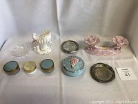 Group of vintage ceramic and glass items including candle holder, jars, vase, jewelry dish and trays arranged on white backdrop.