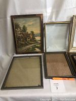 Group of assorted picture frames including one with framed oil painting and others empty with glass panes