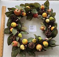 Full view of the square-shaped wreath showing all types of artificial fruits, pinecones, leaves, and berries.
