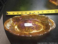Photo showing the full vintage carnival glass tray with an amber iridescent finish, includes a measuring tape for scale indicating about 11 inches in length.