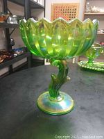 Side view of green carnival glass serving bowl with scalloped edges and curved stem base