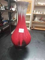 Front and side view of a red ceramic vase with black and gray hues.
