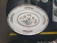 Top view of the white oval serving dish with central bird and floral motif and floral border around rim.