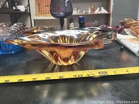 Side view of amber vintage leaf shaped glass bowl with measuring tape showing length about 12 inches.