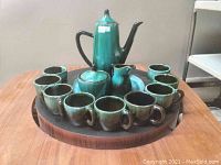 Full view of the BMP vintage ceramic tea set arranged on round wooden tray including teapot with lid, sugar bowl with lid, creamer, and 9 cups.