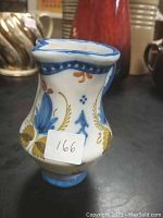 Front and side view showing hand-painted floral motifs and the shape of the ceramic creamer/pitcher.