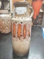 Front and side view of 8-inch vintage West German pottery pitcher/vase with distinct textured speckled glaze and orange vertical accent strips, showing loop handle and flared lip.