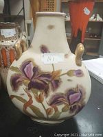 Front view of the vintage vase showing hand-painted purple flowers and gold-toned side handles.