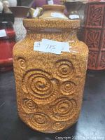 Front and side view of the vintage West German pottery vase with textured circular designs in brown glaze.