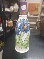 Full side view of ceramic bottle showing hand-painted blue iris flowers with yellow and green leaves, 10.5 inches tall