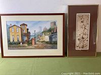Both framed artworks side by side on green tablecloth against white wall: Barbara Ford watercolor on left, Pat Van Gelder lithograph on right.