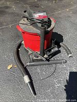 Craftsman red and black 6.0 HP wet dry vacuum showing the main unit, flexible hose with tape, and several vacuum attachments.