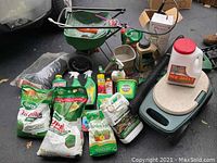 Garden lot showing bags of Scotts Turf Builder fertilizer, spreader, garden stool, sprayer and assorted garden chemicals and tools.