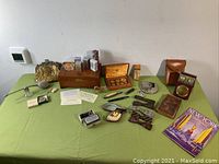 Overview of all vintage items on green table showing pins, coins, pipe, radio, camera, and other accessories
