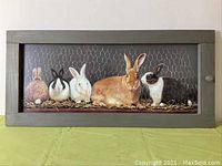 Full frontal photo of the framed limited edition print showing five rabbits along with chicken wire and straw background with rustic wood frame
