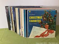 View of 30 vinyl record albums stacked showing variety of album art and thicknesses.