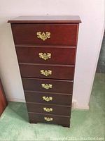 Full front view of the wooden media/CD cabinet showing six drawers with brass handles