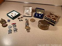 Overview of men’s jewelry and military items including pins, watch, compass, money clip, cufflinks, buttons, and decorative boxes.