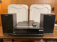 Front view of Sony SuperBetaTheater SL-HFT7 Beta VCR and two SS-X210 speakers with white storage bins in the background.