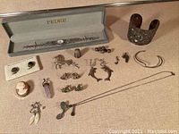 Complete view of jewelry including Pedro watch in box, 800 silver cuff bracelet, earrings, thimble, cameo brooch, pendants, and cufflinks arranged on flat surface