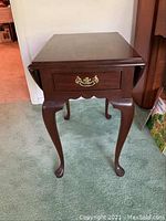 Full view of drop leaf end table with leaves down, showing solid wood top, cabriole legs, and brass handle drawer.