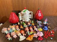 Wide view of dolls and large red strawberry cases on table