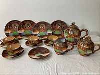 Overview of the complete vintage china tea set including tea pot, creamer, sugar bowl, plates, saucers, and tea cups, all with hand-painted Oriental motifs and dragon designs.