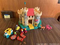 Photo of entire Fisher Price Play Family Castle set with castle, toy figures, carriage, furniture, horses arranged on table.