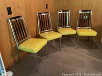 Four vintage kitchen chairs lined up side by side showing overall design and condition.