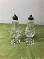 Front view of both Waterford crystal salt and pepper shakers with black and silver screw-on lids