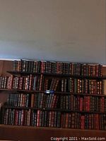 Three-tiered shelf packed with leather-bound books featuring gilt spine decoration