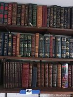 Three-shelf view showing multiple leather-bound editions with gilt spines