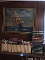 Framed seascape painting in gold wood frame depicting a sailing ship at sea