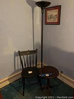 Floor lamp, Tufts University chair, and small round table in corner with blue carpet and beige baseboard.