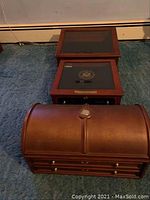 Two wooden coin collector boxes shown stacked, one with glass top and another with curved lid