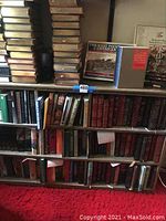 Full bookcase showing shelves filled with hardcover books and top surface
