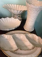 Four Lenox white porcelain pieces: three-section serving dish, large platter, pedestal bowl, and embossed vase.