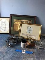 Overall lot with framed items, glassware, and figurines arranged on the floor